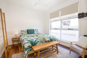 um quarto com uma cama, uma cadeira e uma janela em LegaSea Lodge - Pet Friendly Beachfront with Plunge Pool em Shellharbour