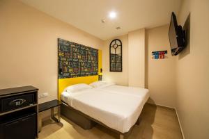 a small bedroom with a bed and a tv at Fragrance Hotel - Oasis in Singapore