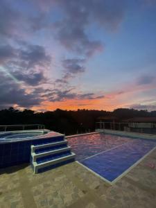 une grande piscine avec un coucher de soleil en arrière-plan dans l'établissement Finca Hotel Las Palmeras, à Armenia