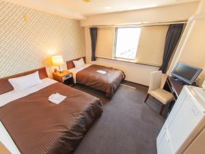 una camera d'albergo con due letti e una televisione di HOTEL LiVEMAX BUDGET Sagamihara a Sagamihara