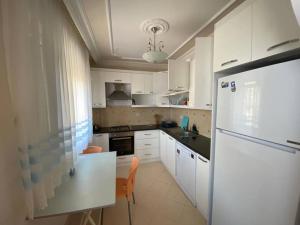 cocina con armarios blancos y nevera blanca en Turkish riviera sea view detached villa, en Gazipasa