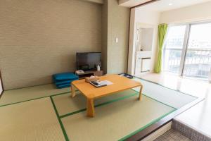 a living room with a table and a tv at 紀州鉄道片瀬江ノ島ホテル in Fujisawa