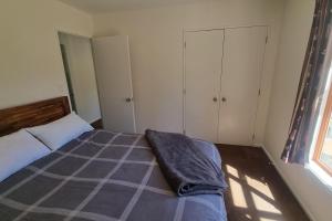 ein Schlafzimmer mit einem Bett mit einer Decke darauf in der Unterkunft Sherwood Ranch Cottages - 403 Woodbank Road in Hanmer Springs