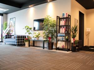 a lobby with a couch and a tv on a wall at HOTEL LiVEMAX Sagamihara Ekimae in Sagamihara