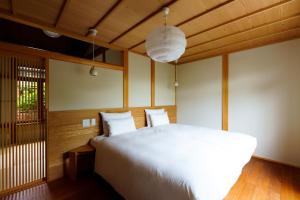 a bedroom with a large white bed and wooden floors at hotori in Kyoto