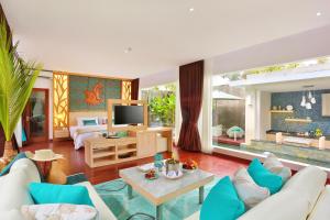 a living room with a couch and a tv at The Leaf Jimbaran Luxury Villas in Jimbaran