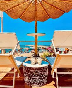 eine Terrasse mit zwei Stühlen und einem Sonnenschirm und dem Strand in der Unterkunft Green Garden Oasi in Cinisi