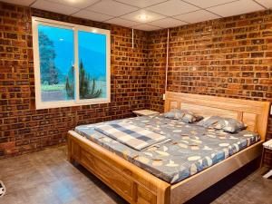 um quarto com uma cama numa parede de tijolos em Eliss Garden Coffee & Homestay em Ấp Thiện Lập