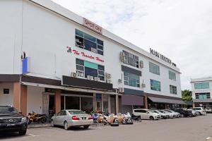 ein großes weißes Gebäude mit Autos auf einem Parkplatz in der Unterkunft SPOT ON 89805 The Traveler Home in Sibu