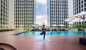 Eine Frau, die eine Yoga-Pose vor einem Pool macht. in der Unterkunft Louis Kienne Hotel & Service Apartment in Cikarang