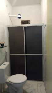a bathroom with a toilet and a glass shower door at Casa 01 simples e aconchegante em Maragogi in Maragogi