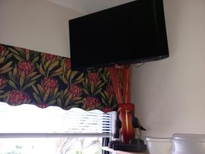 a flat screen tv hanging on a wall next to a window at Fynbos Single Stay in Langebaan