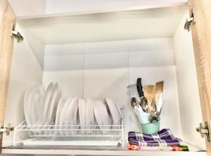 um armário branco com pratos e utensílios em Sмарт студія з терасою !! em Yuzhne