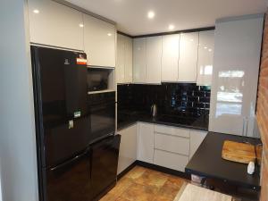 a kitchen with a black refrigerator and white cabinets at Szewnia Dolna in Szewnia
