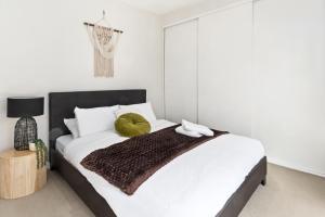 Un dormitorio con una cama con una almohada verde. en Escape To Melbourne - Stylish 1 Bedroom-Gym - Aircon -Balcony en Melbourne