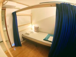 a small room with a bunk bed and blue curtains at Guesthouse LuLuLu 無料朝食 街まで路面電車8分 コンビニ隣 in Kochi