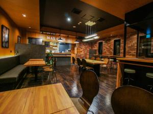un restaurante con bar, mesas y sillas en HOTEL LiVEMAX Minamihashimoto Ekimae en Sagamihara