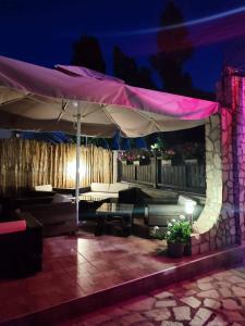 a patio with a table and an umbrella at night at Enjoy Guest House in Golden Sands