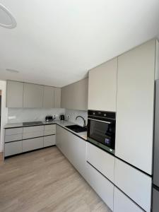 una cocina blanca con armarios y electrodomésticos blancos en The Nice Apartment, en Domžale
