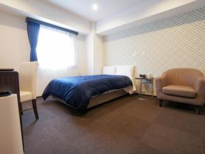 a bedroom with a bed and a chair and a window at HOTEL LiVEMAX Minamihashimoto Ekimae in Sagamihara