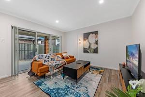 sala de estar con sofá y mesa en KozyGuru / Austral / 5Bed House / NAU015, en Horningsea Park