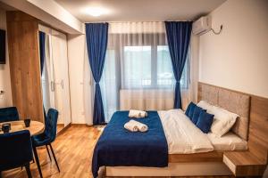 een slaapkamer met een bed met blauwe lakens en een tafel bij Apartman Zlatanovic Jagodina in Jagodina