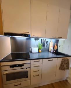 a kitchen with white cabinets and a stove top oven at Cosy apartment with a relaxing sauna and a balcony in Helsinki