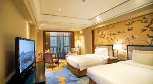 a hotel room with two beds and a flat screen tv at Wyndham Grand Plaza Royale Ningbo in Ningbo