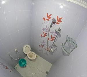 baño con aseo y un estampado de flores en la pared en Kenayan Homestay Jogja, en Salakan