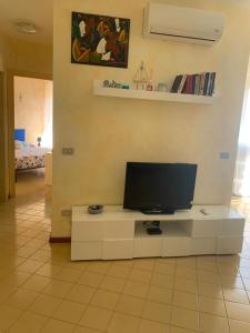 un salon avec une télévision sur une table blanche dans l'établissement palau casa vacanza le ginestre, à Palau