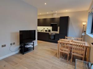 a living room with a flat screen tv and a table at Dream apartment Finchley 4 min walk to the train in Hendon