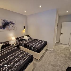 1 dormitorio con 2 camas y pasillo con puerta en Dream apartment Finchley 4 min walk to the train en Hendon