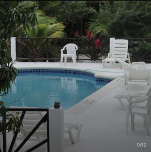 a swimming pool with chairs and a table and chairs at Aqua Studio 6 in Negril