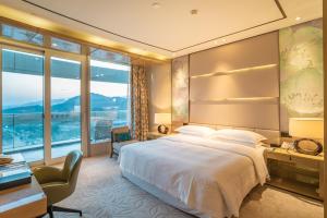 um quarto de hotel com uma cama grande e uma secretária em Sheraton Huzhou Taihu Lake Hot Spring Resort & Spa em Huzhou