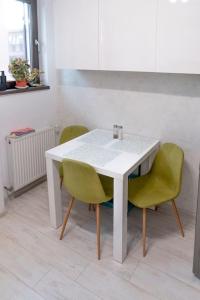 a white table and two green chairs in a kitchen at Apusului Residence Modern 2 Bedroom Apartment in Roşu