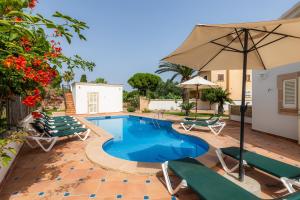 uma piscina com cadeiras e um guarda-sol em Villa Sa Coma em Sa Coma