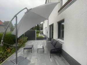 a patio with an umbrella and chairs and a couch at Modernes und helles Mini-Haus in Peine in Peine