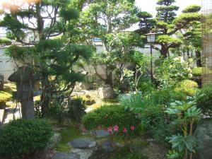 a garden with flowers and trees and a street light at Ryokan Ginsuikaku - Vacation STAY 40409 in Maizuru