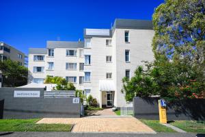 a large white building with a fence in front of it at Spacious 3 Bedroom Delight - Shops & Beaches ZG1 in Caloundra