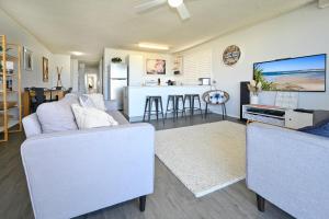 a living room with two white couches and a kitchen at Spacious 3 Bedroom Delight - Shops & Beaches ZG1 in Caloundra
