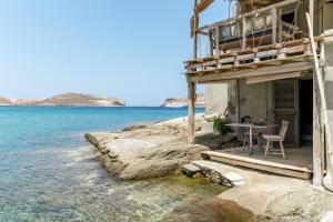 a house on the water with a table and chairs at The Fishermans Experience Tinos in Platiá