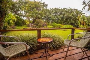 two chairs and a table on a deck with a garden at Hostal Uruhao in Hanga Roa