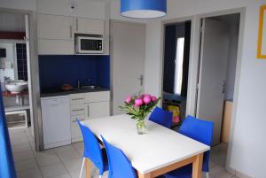 Una cocina con una mesa con un jarrón de flores encima. en VVF Golfe du Morbihan Sarzeau Arzon, en Sarzeau