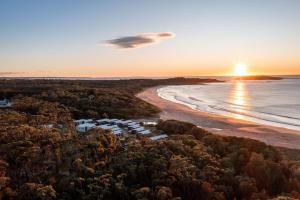 an aerial view of a beach at sunset at BIG4 Tasman Holiday Parks - Racecourse Beach in Bawley Point