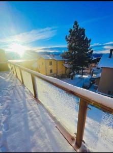 a snow covered balcony with the sun in the background at Appart hyper centre Font Romeu in Font-Romeu-Odeillo-Via
