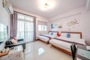 a bedroom with two beds and a tv and a window at Shanghai Time in Hualien City