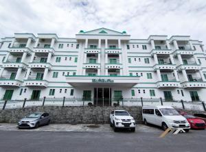 a large white building with cars parked in front of it at Mciti Suites by Evernent in Miri