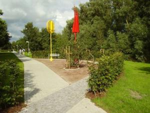 um parque com um guarda-chuva vermelho e um passeio em Ferienhaus in Dornumersiel 20-157 em Dornumersiel