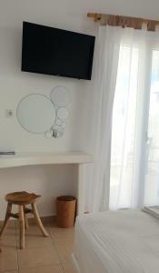 1 dormitorio con 1 cama y TV en la pared en Ilias Place, en Ios Chora
