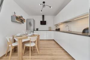 cocina con mesa de madera, sillas y encimera en Spacious Apartment with Balcony near the Slavic Hill Wrocław by Renters Prestige, en Wroclaw